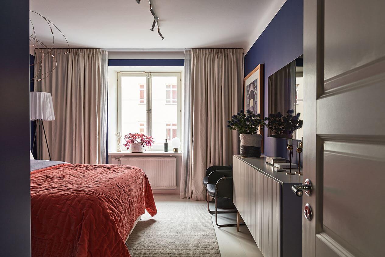 An Art-Filled Scandinavian Apartment 15 dark-violet-blue-bedroom-orange-red-bedding-nordroom