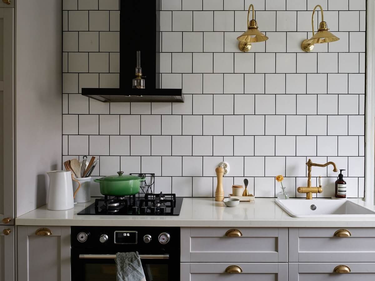 A Charming Swedish Apartment with a Cottage-Style Kitchen 16 kitchen gray cabinets white tiles brass fittings nordroom
