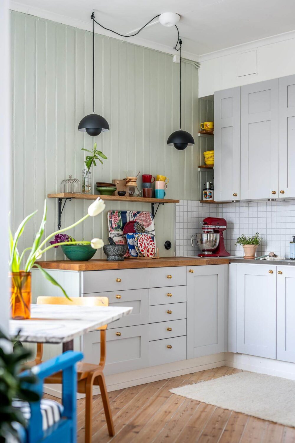 Primary Color Accents in a Light Swedish Apartment 17 kitchen-light-green-walls-black-pendants-nordroom