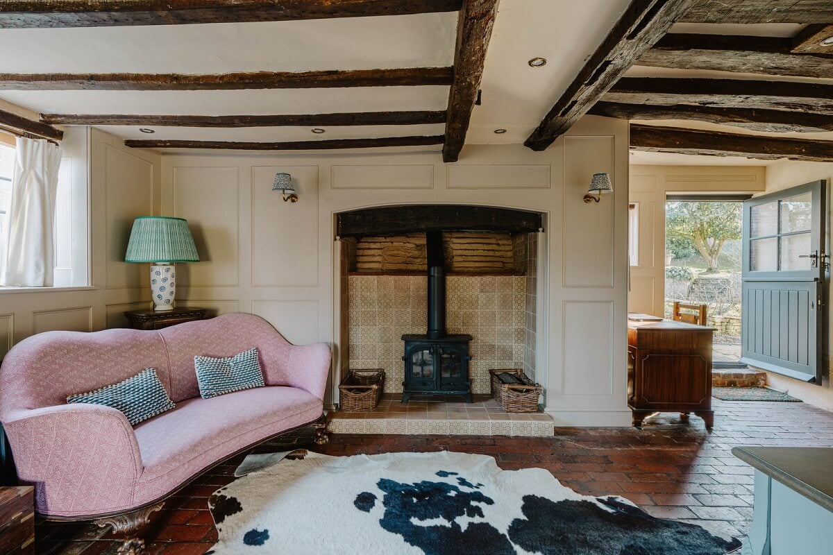 A Cozy Historic English Country House with Exposed Beams 9 living room pink sofa fireplace exposed wooden beams nordroom