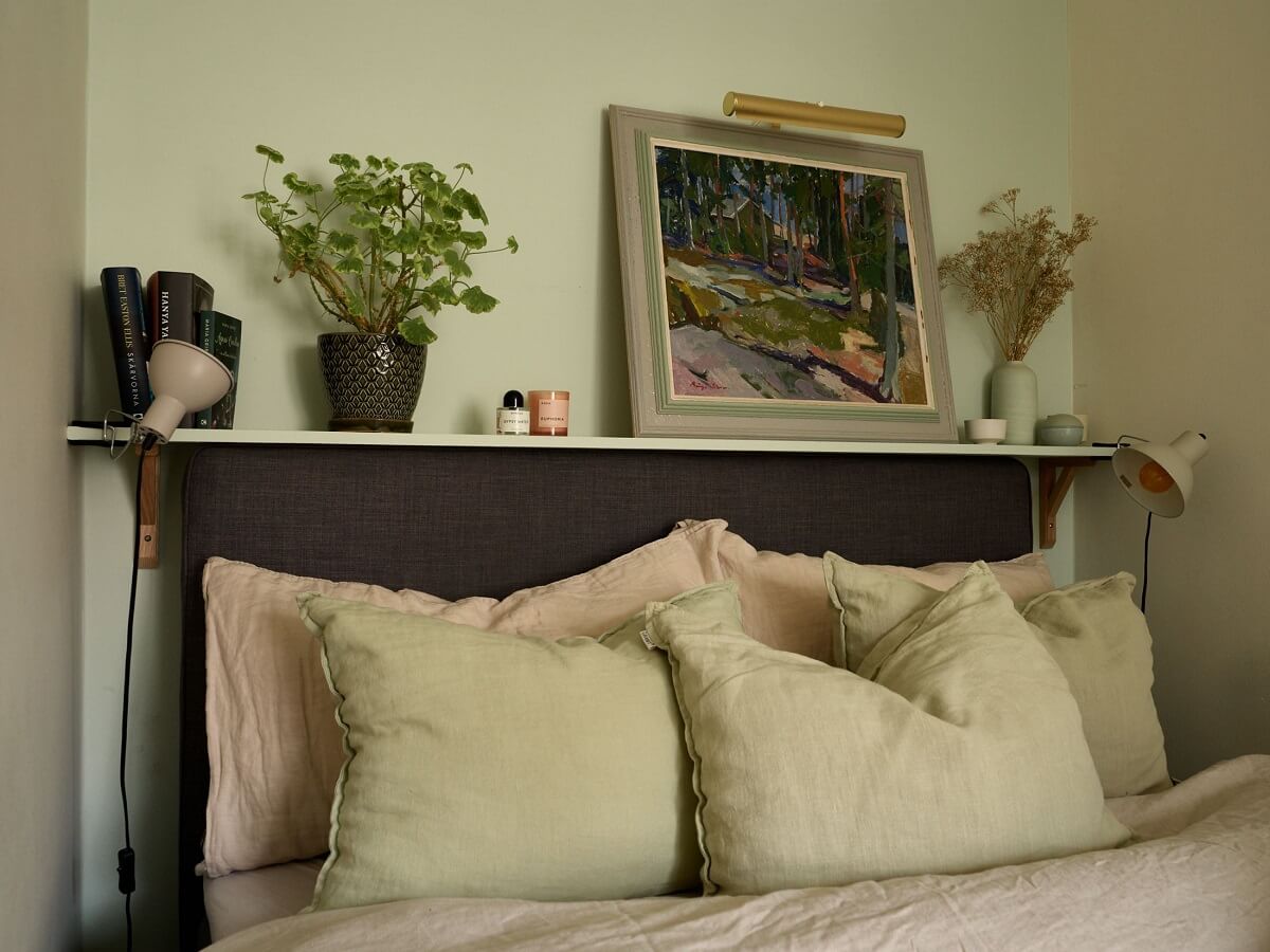 A Charming Swedish Apartment with a Cottage-Style Kitchen 9 shelf above bed headboard in narrow bedroom with pale green walls nordroom