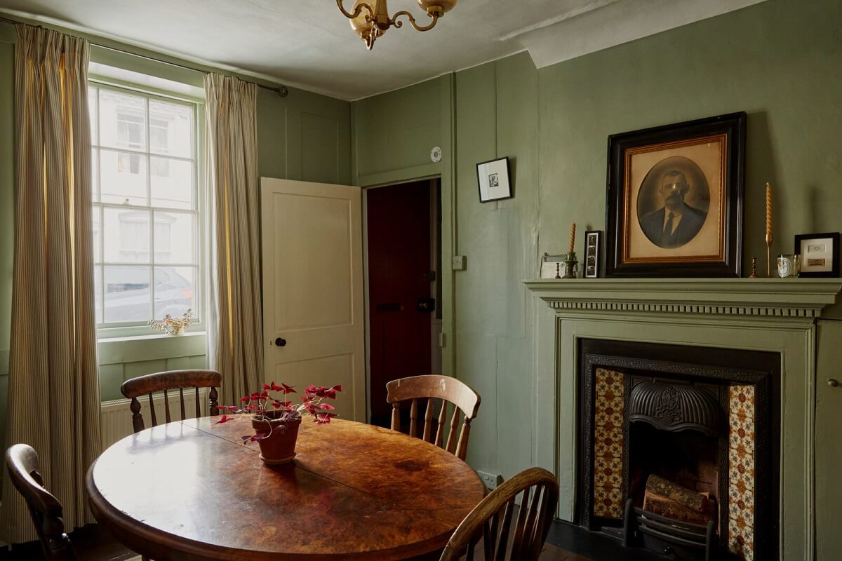 A Cozy Home with Exposed Beams in a Former Post Office 4 dining-room-green-walls-fireplace-antique-round-table