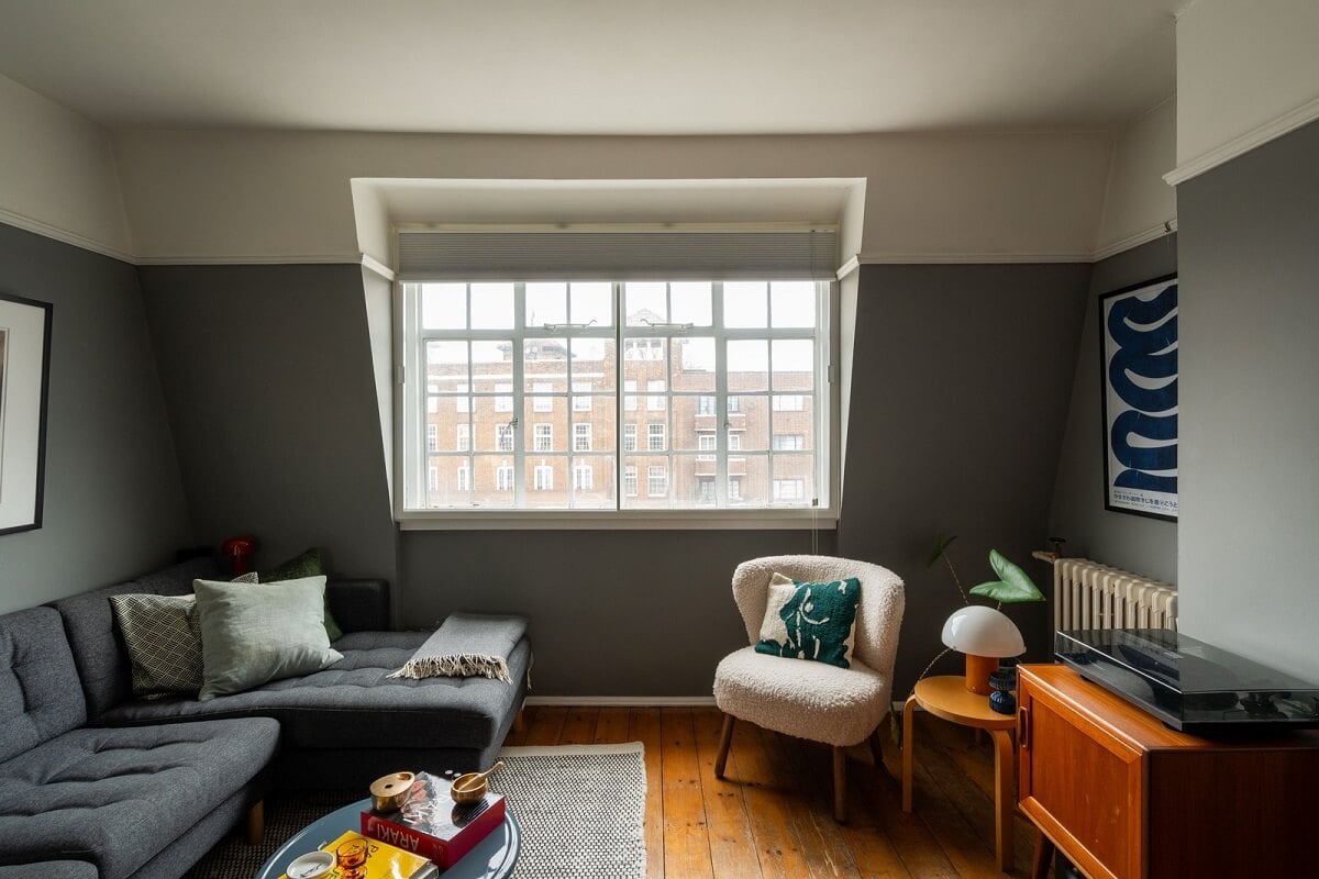 A Charming Top-Floor Apartment in an Art Deco Building 1 living room gray walls slanted ceiling warm wooden floor nordroom