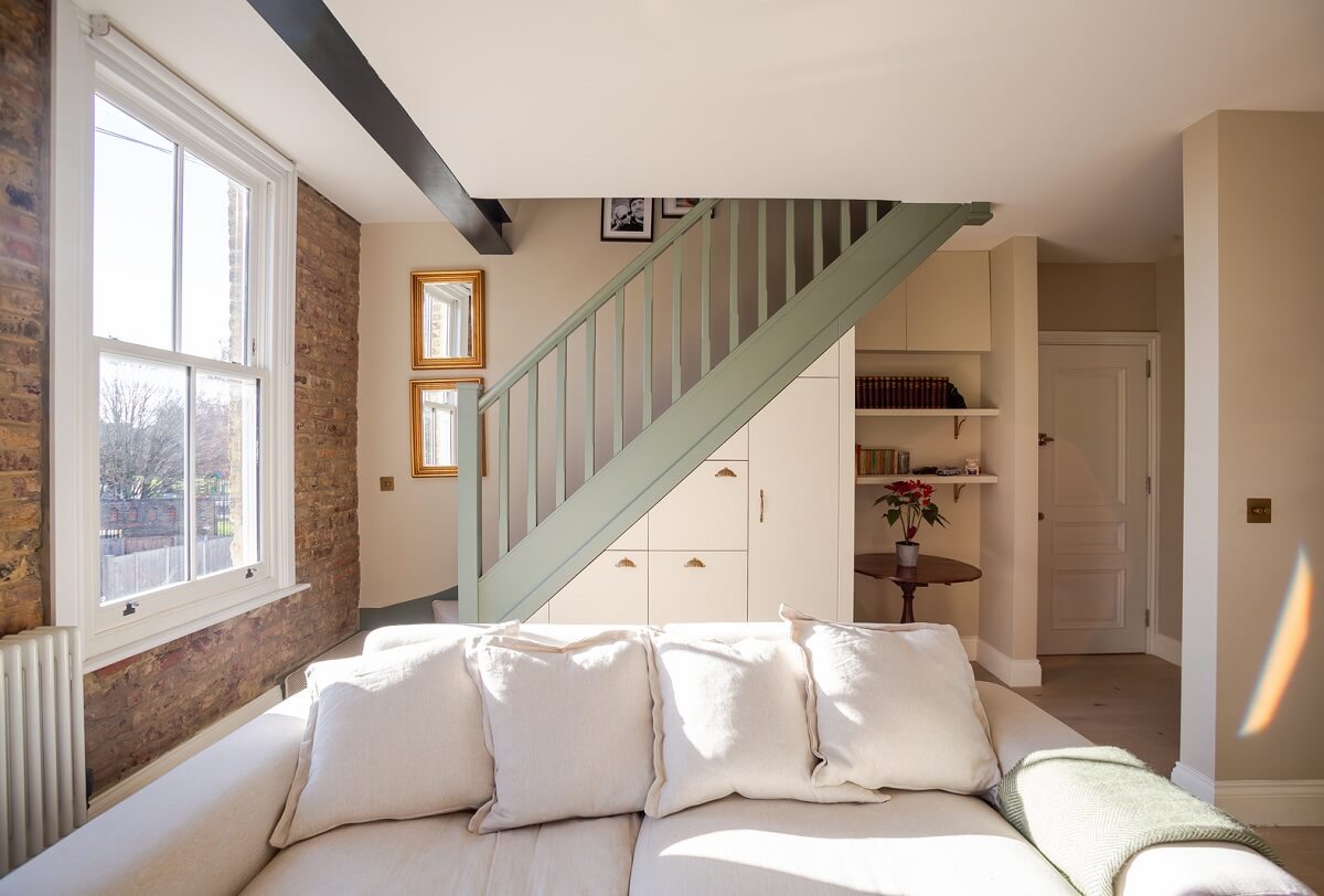 An Exposed Brick Wall in a London Duplex Apartment 4 living room with storage under the stairs