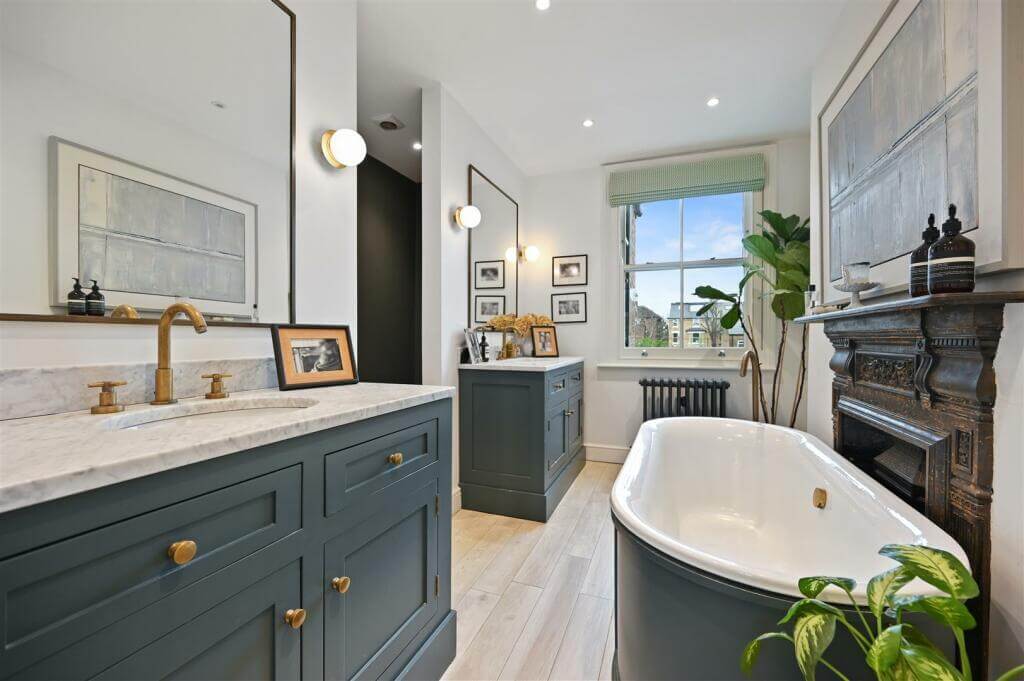 A London Family Home with Blue Color Accents 11 bathroom with gray cabinets and freestanding bath