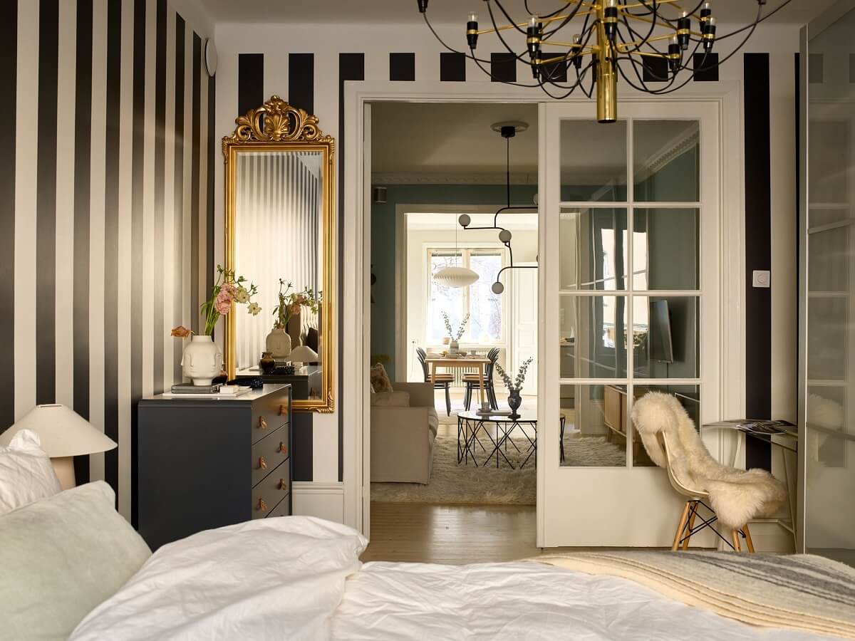 A Social Scandinavian Apartment with a Light Blue Living Room 16 bedroom with striped wallpaper and gilded mirror