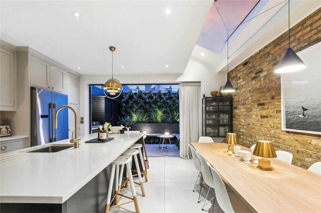 An Extended Victorian House Decorated in Gray Tones 3 exposed brick wall in extended kitchen space with island