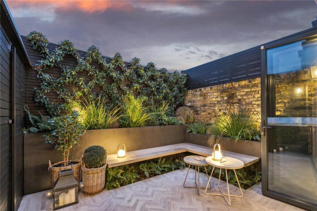 An Extended Victorian House Decorated in Gray Tones 7 garden with built in seating bench at night