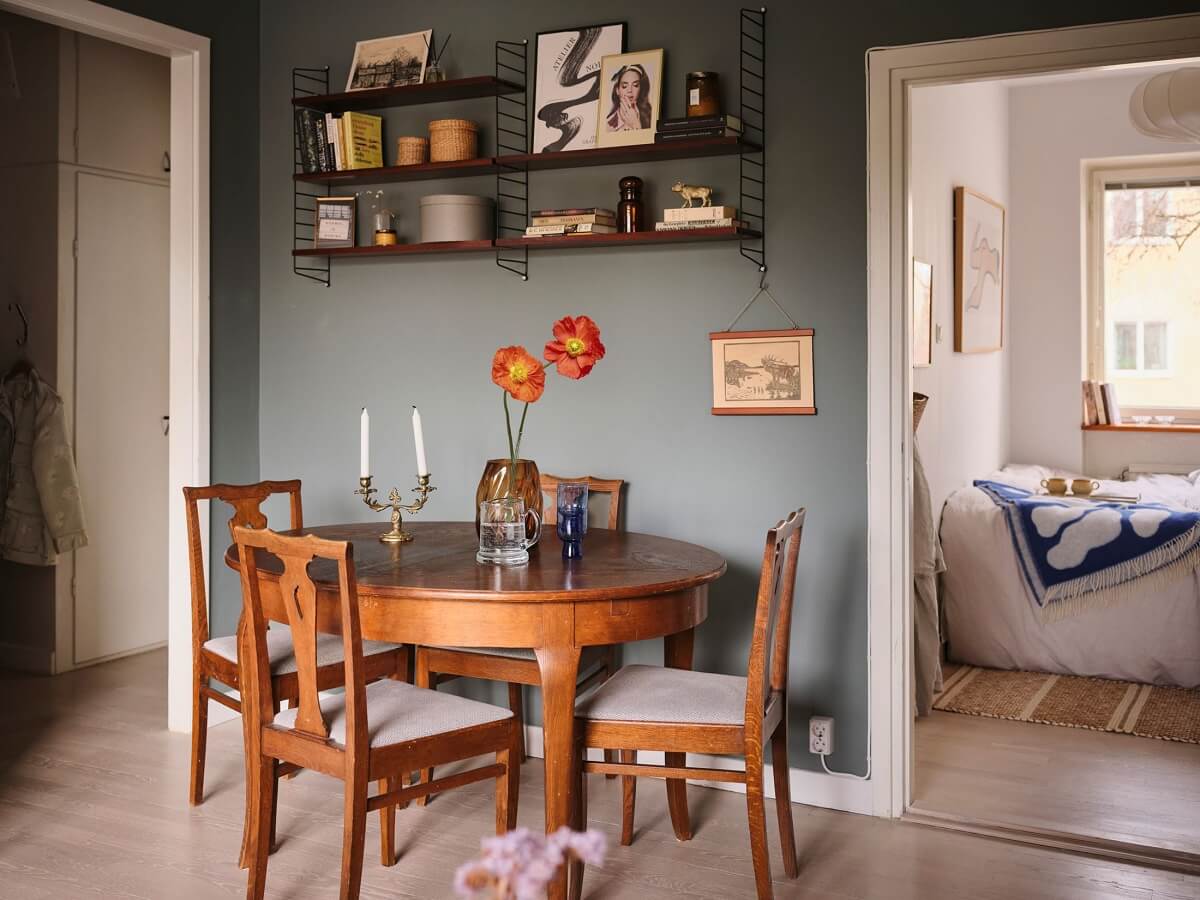 A Small Midcentury Apartment in Stockholm 5 gray living room with round wooden dining table and shelves
