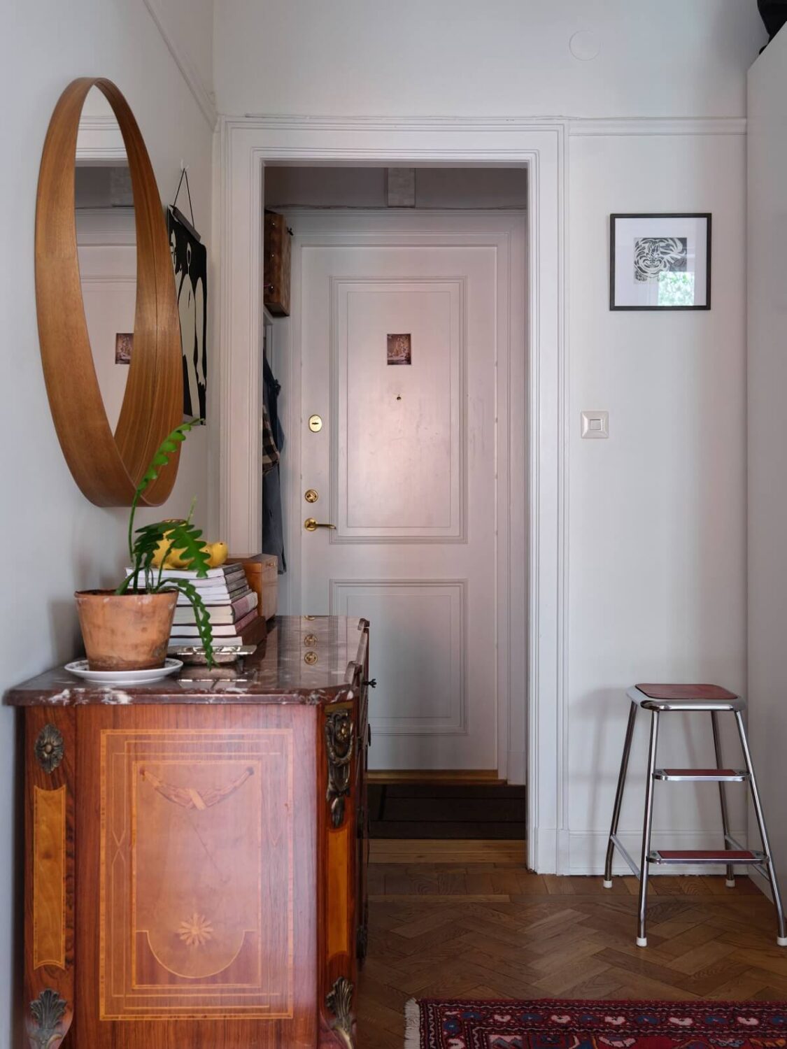 A Small Gray Apartment with Industrial Glass Walls 20 hallway with wooden floor and round wall mirror