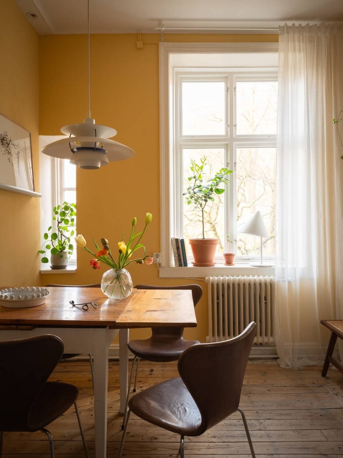 A Scandinavian Apartment with a Warm Living Room and Rounded Walls 13 kitchen dining table and yellow walls