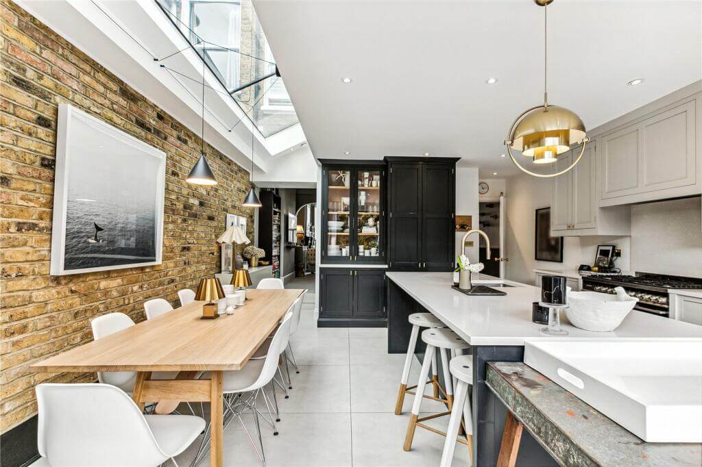 An Extended Victorian House Decorated in Gray Tones 5 kitchen with dining room and exposed brick wall
