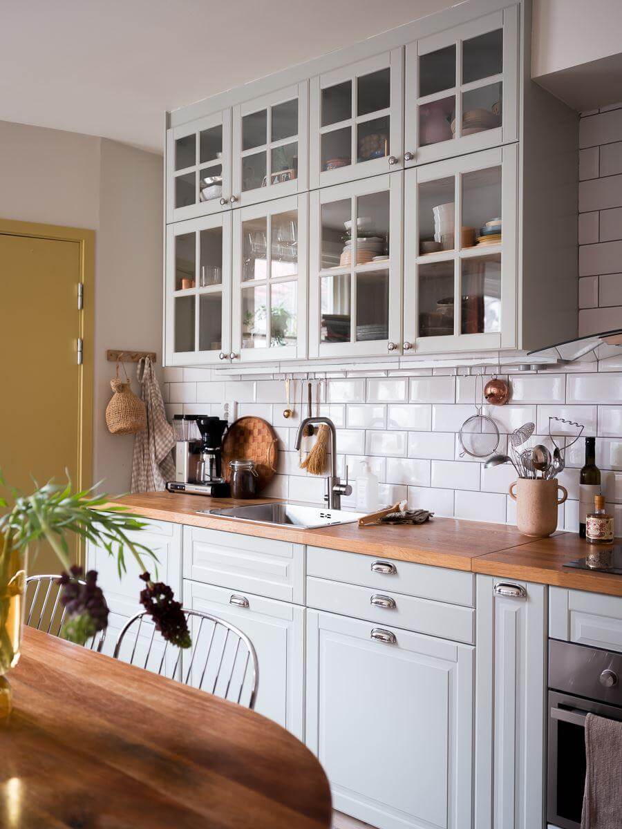 A Beautiful Color Palette in a Scandinavian Family Apartment 8 kitchen with glass upper cabinets