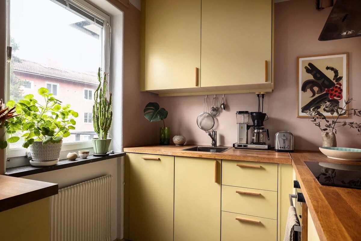 A Cozy Studio Apartment with a Yellow Kitchen 14 kitchen with yellow cabinets and pink walls