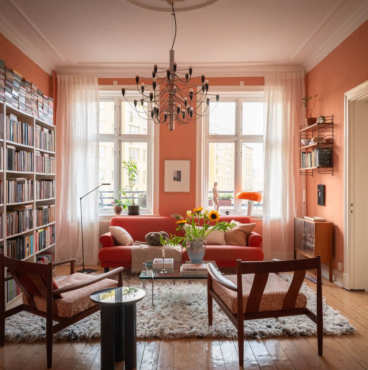 A Scandinavian Apartment with a Warm Living Room and Rounded Walls 1 living room with orange pink terracotta shade on walls and bookshelves
