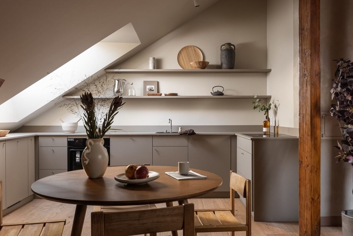 An Attic Apartment in Oslo with Exposed Wooden Beams 8 modern gray kitchen with round wooden dining table