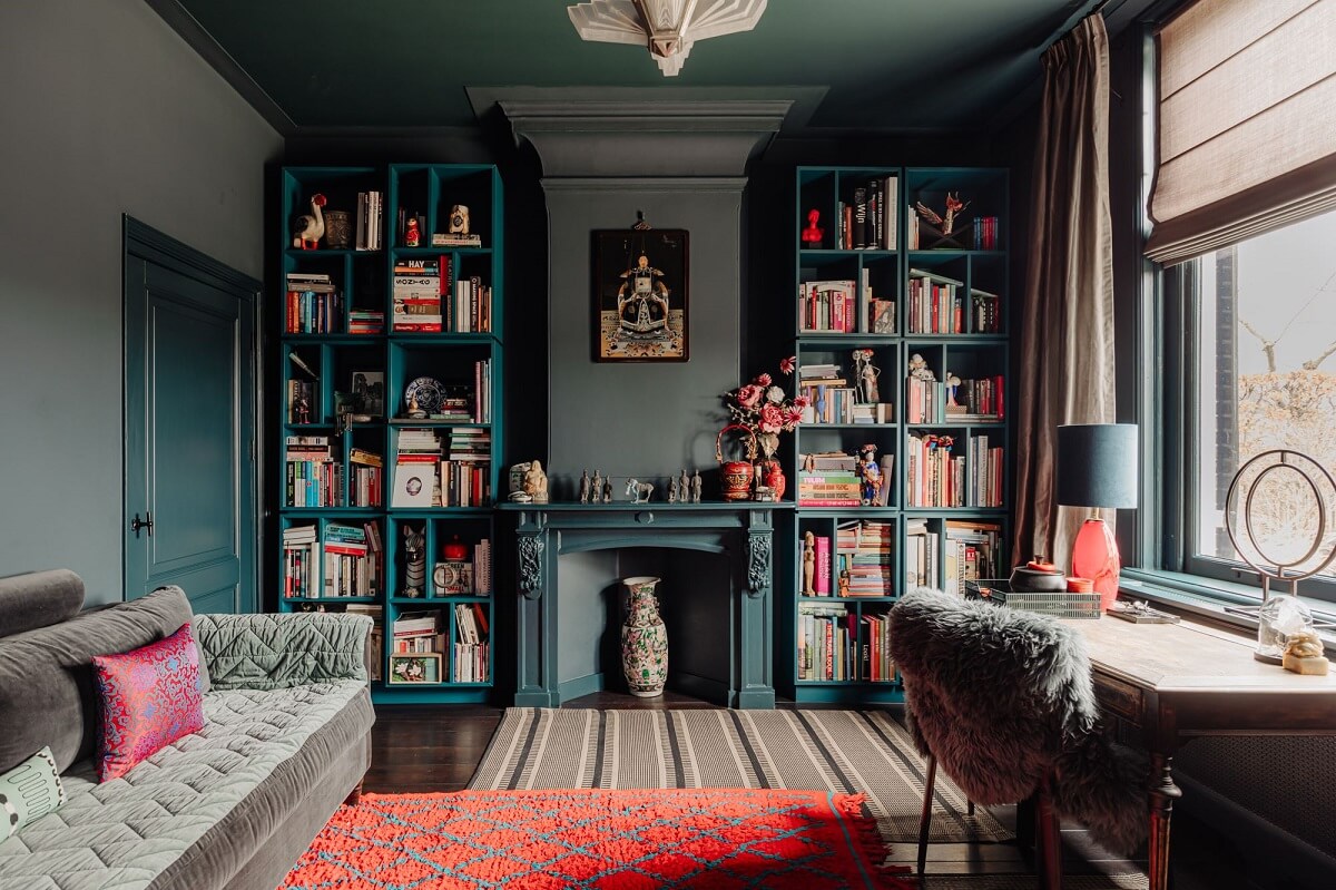 A Beautifully Renovated Dike House in The Netherlands 3 moody living roo with bookcases and blue fireplace