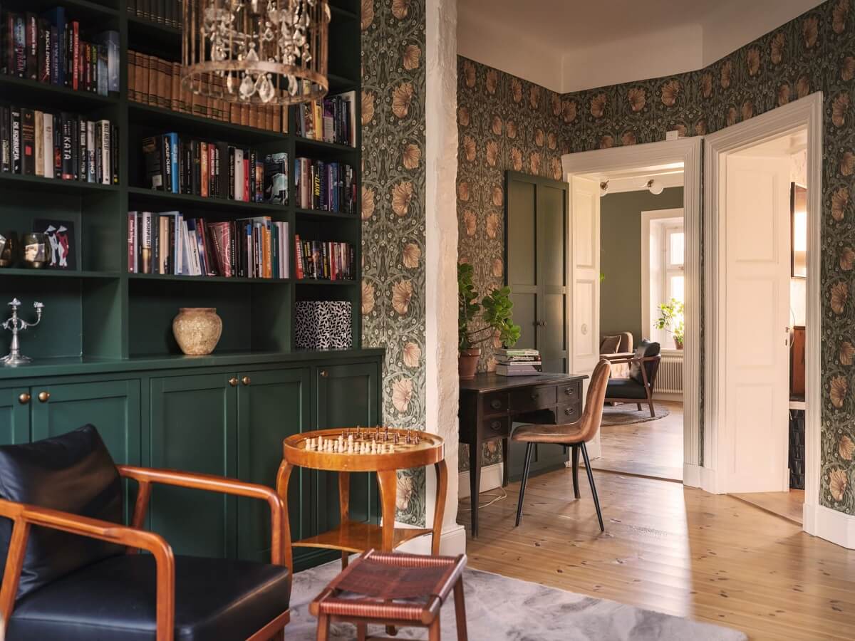 A Classic Swedish Apartment Decorated in Green and Pink Tones 14 reading room with green bookcases and william morris wallpaper