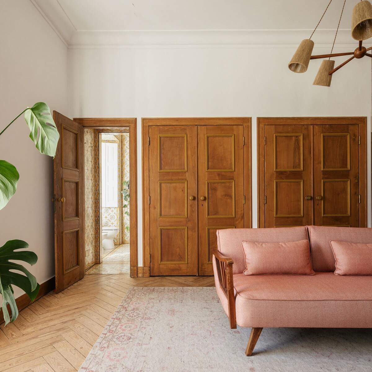 A Renovated Pink Manor House in Portugal 8 sitting room with pink sofa and wooden doors nordroom