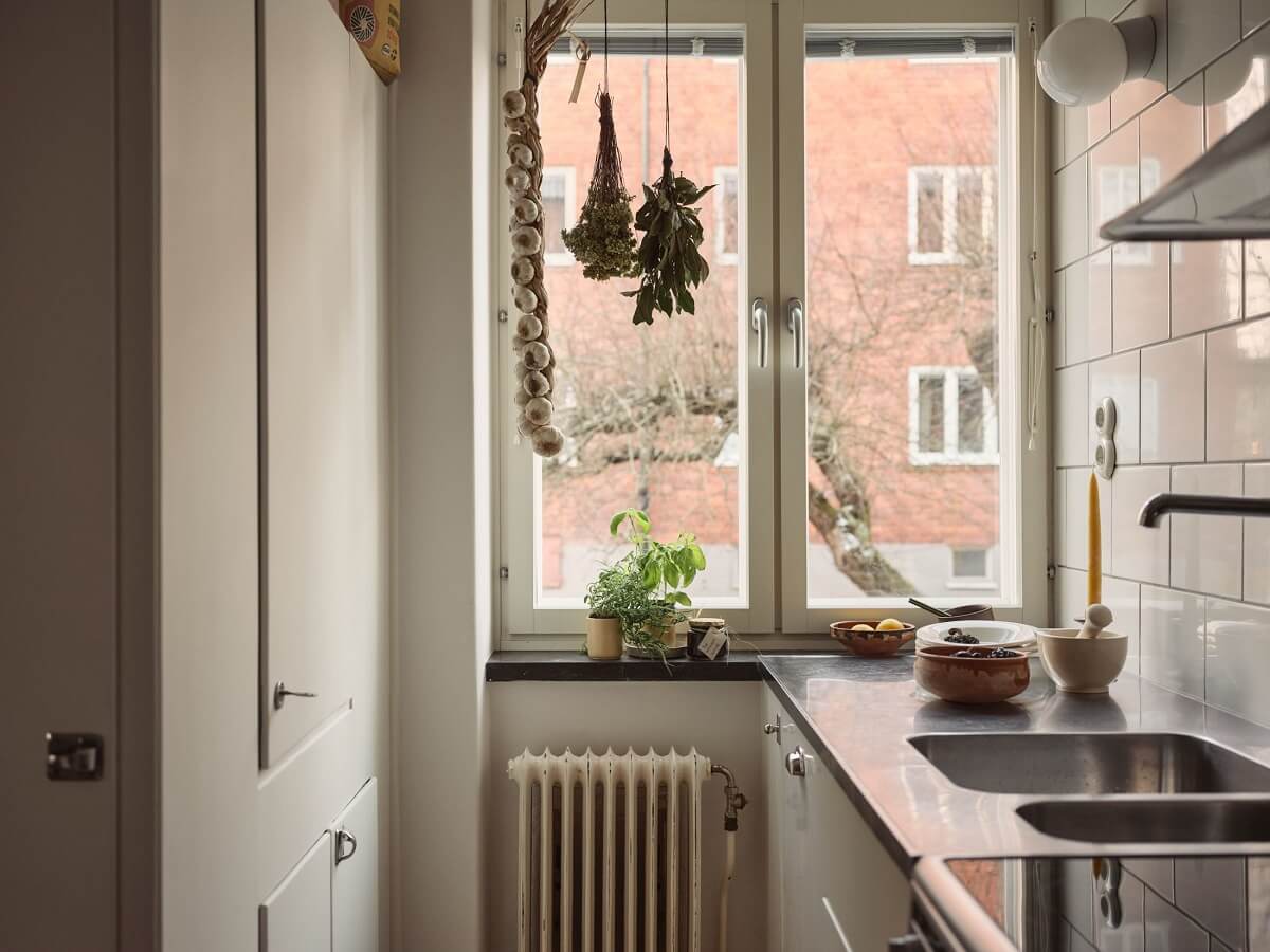 A Small Apartment with a Cozy Dining Nook 10 white kitchen with large window