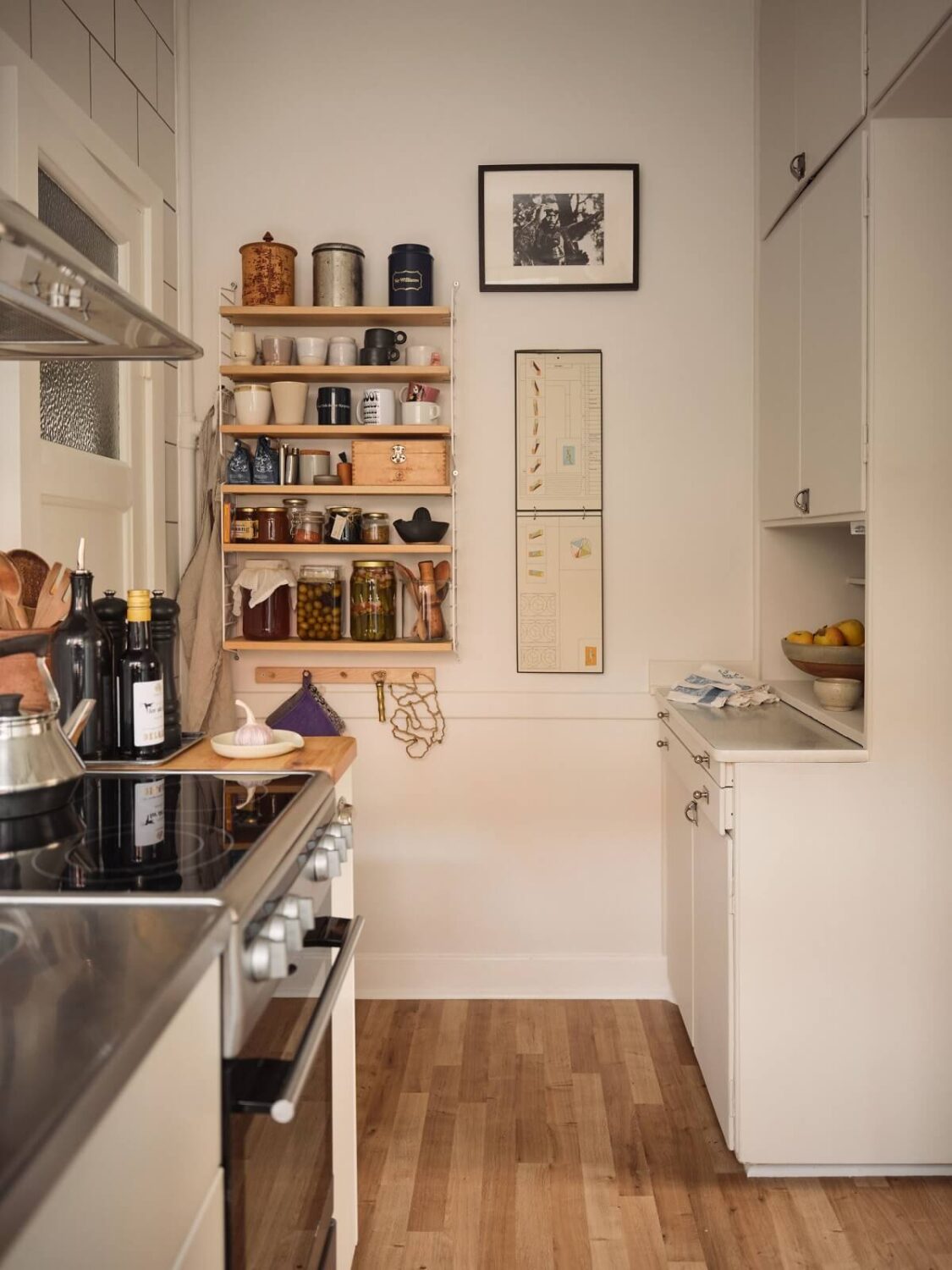 A Small Apartment with a Cozy Dining Nook 11 white kitchen with wooden shelves