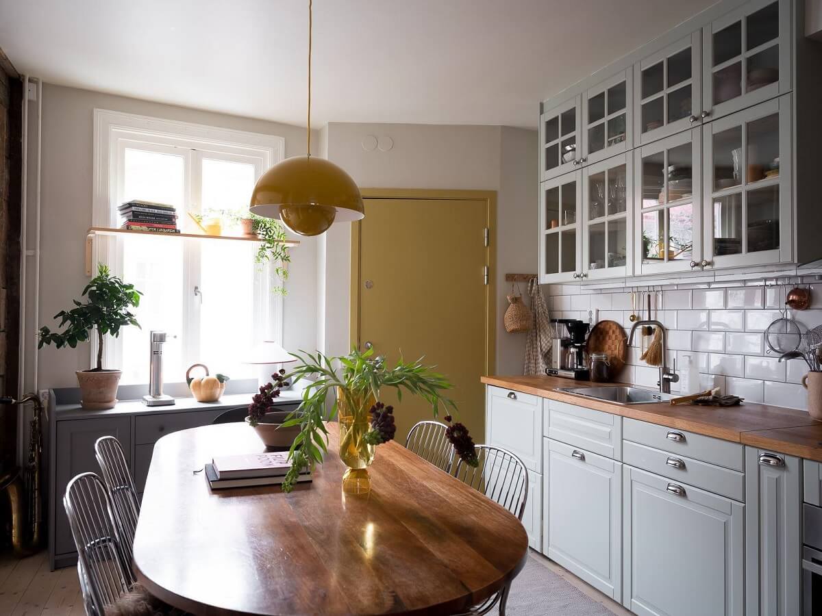 A Beautiful Color Palette in a Scandinavian Family Apartment 9 yellow door and pendant in kitchen with dining table