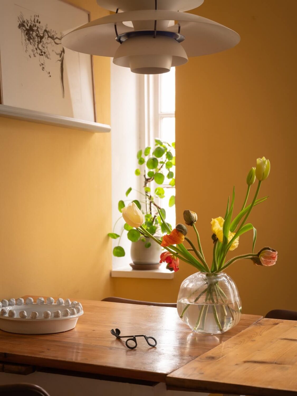 A Scandinavian Apartment with a Warm Living Room and Rounded Walls 14 yellow wall and kitchen table with flowers