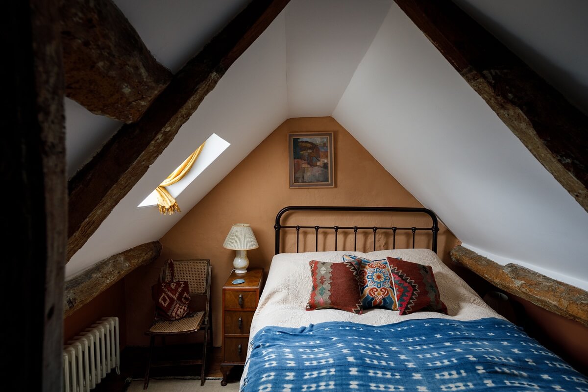 A Charming English Cottage Filled with Historic Character 19 attic bedroom with terracotta brown walls and wooden beams