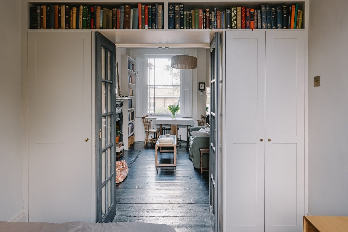 A Small London Apartment Filled with Books 13 bedorom with built in wardrobes and bookshelf above the door