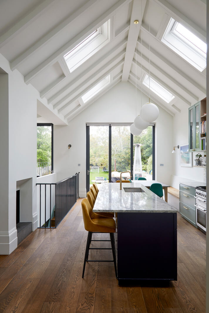 A Colorful London Family Home Renovated by Fraher & Finlay 12 dark blue kitchen island with yellow bar stools