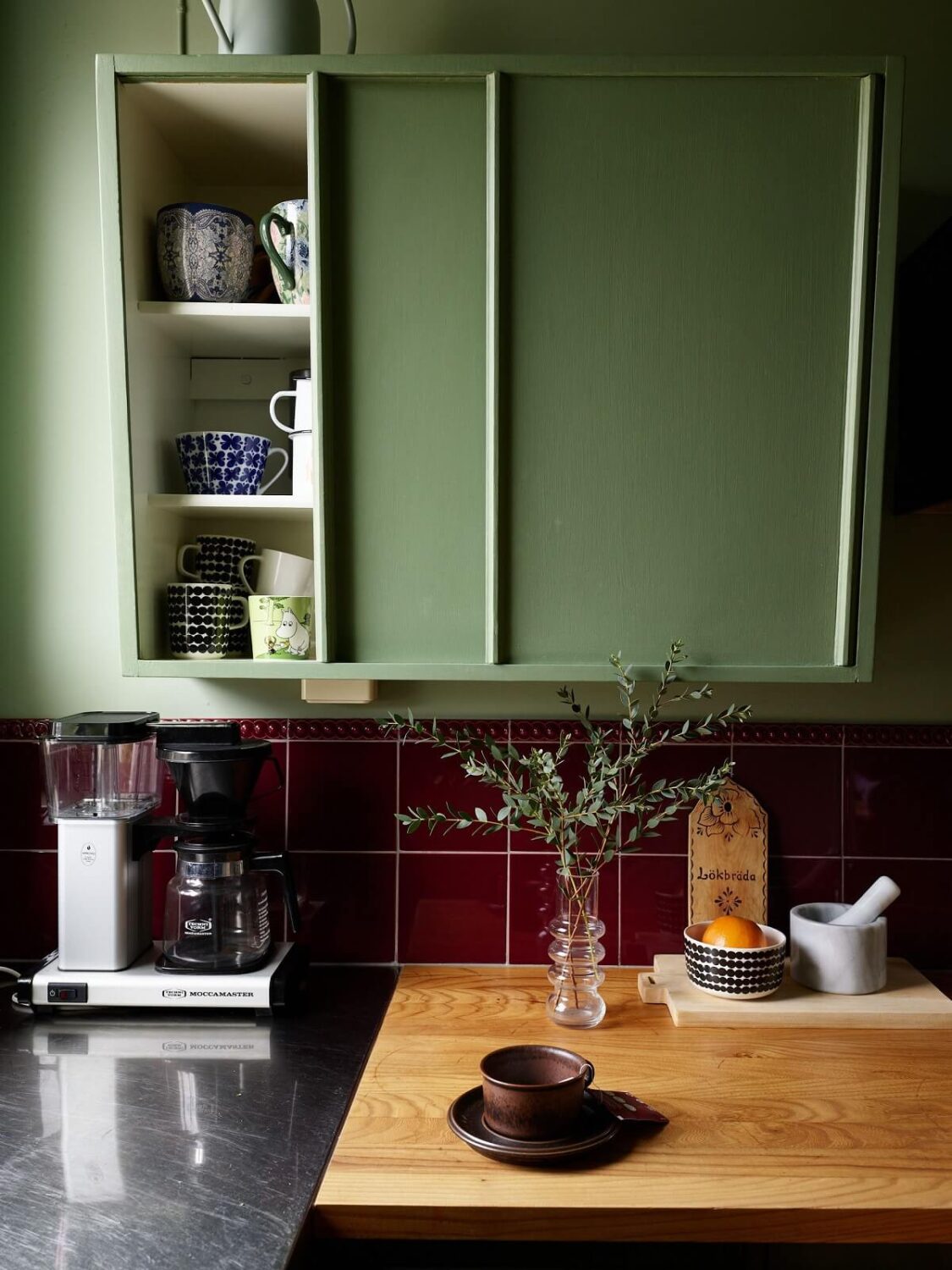Revisiting a Small Green and Pink Midcentury Apartment 2 green midcentury kitchen cabinets