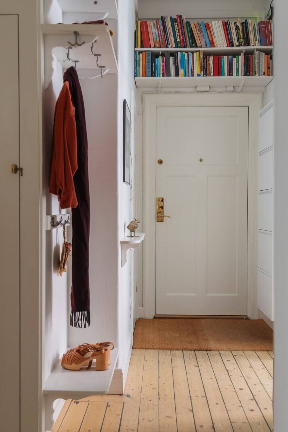 Period Details and Light Rooms in a Scandinavian Apartment 24 hallway with bookshelves above the door
