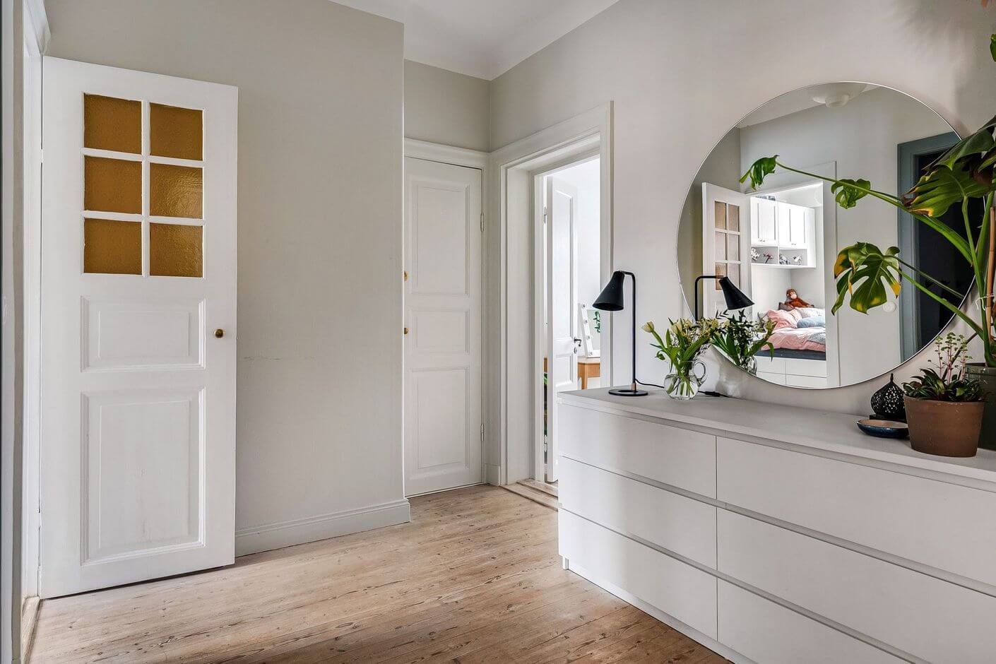 A Swedish Family Apartment with a Butter Yellow Kitchen 9 hallway with white malm and large round mirror