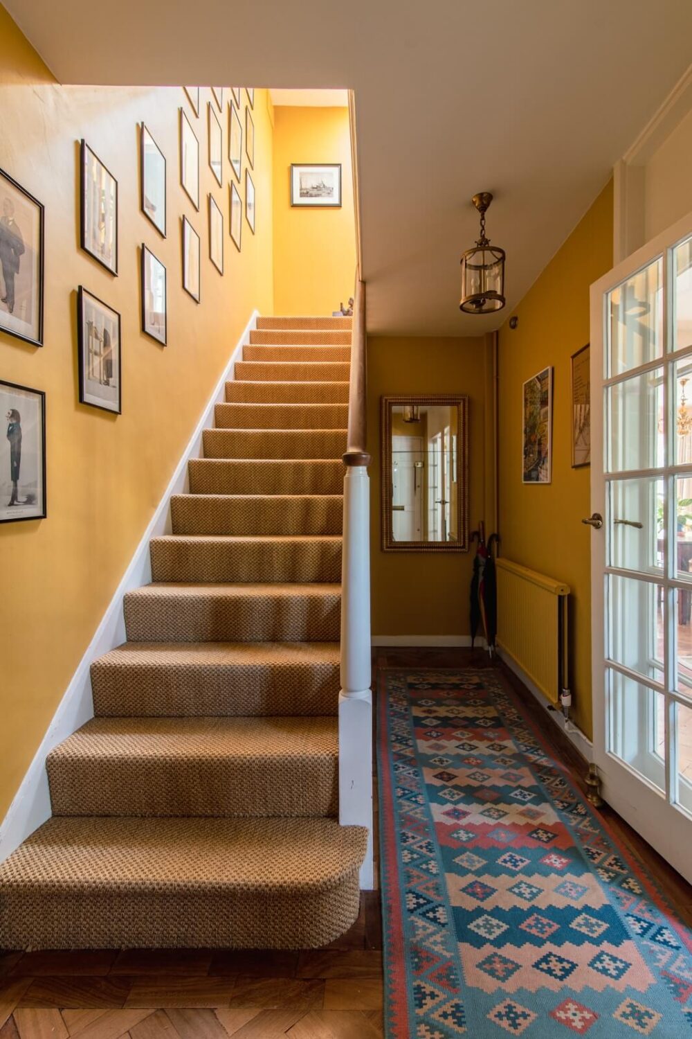 A Colorful Neo-Georgian House in London 13 halway with yellow walls and blue runner