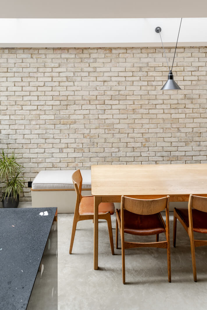 A Light London Family House with a Modern Extension 10 kitchen dining space with bench and brick wall