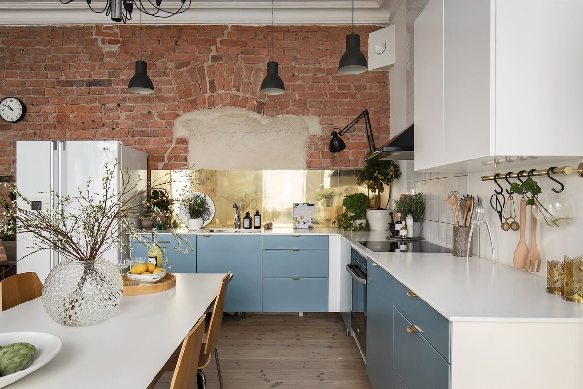 A Swedish Apartment with an Exposed Brick Wall 1 kitchen with blue cabinets and brick wall