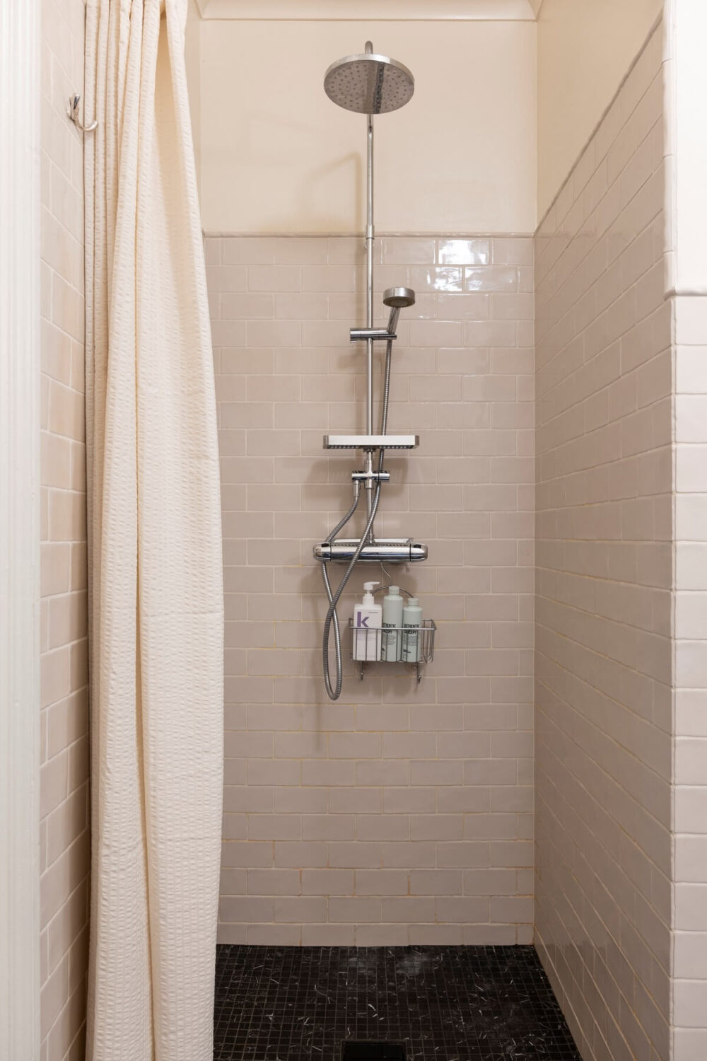A Pink Apartment with a Black Kitchen 11 shower with black floor tiles