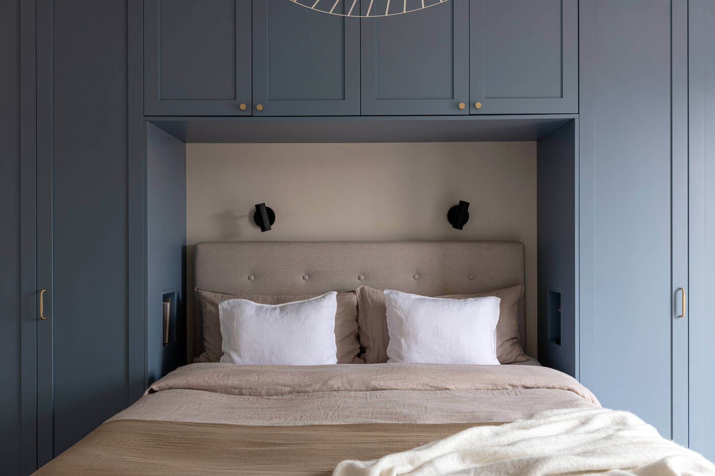 A Stylish Renovated Stockholm Apartment with Built-In Storage 11 bed surrounded by blue wardrobes
