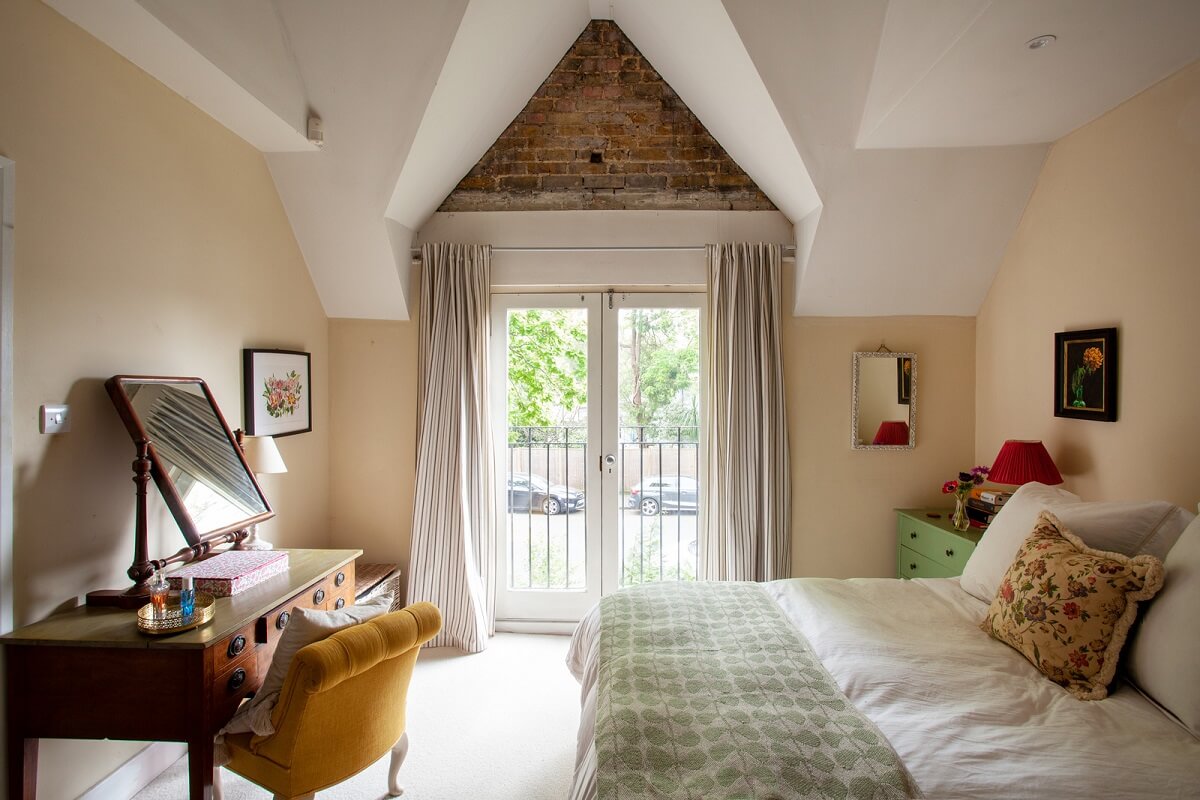 Charming Cottage Style in a London Maisonette 9 beige bedroom with pitched ceiling and brick accent wall