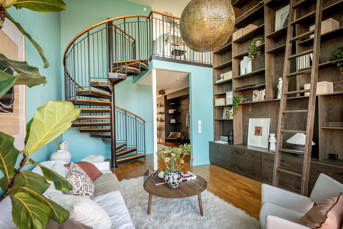 Floor-to-Ceiling Bookcases and Windows in a Loft Style Apartment 6 blue living room with bookcases and spiral staircase