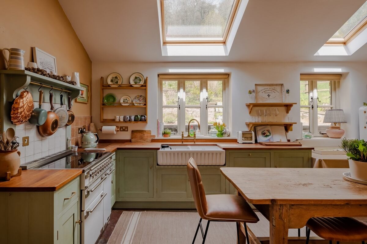 Ochre Yellow and Green Tones in a Cozy Welsh Cottage 2 cottage kitchen with butler sink under window and farmhouse table nordroom