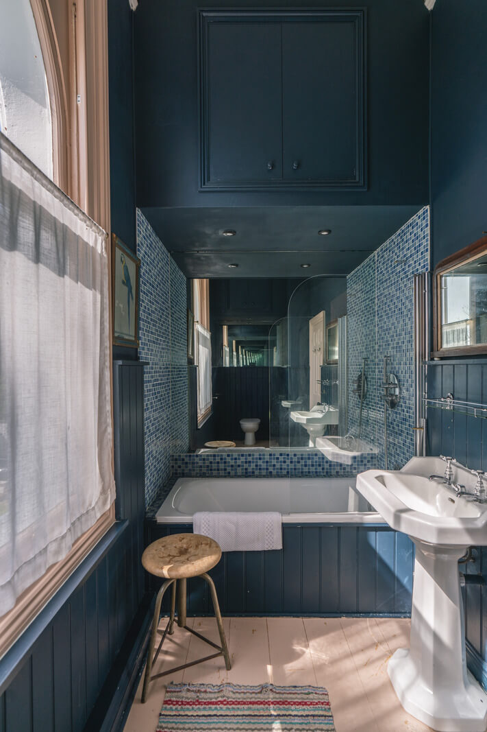 Grand Rooms and Vibrant Colors in an English Country Home 13 dark blue bathroom with large mirror nordroom