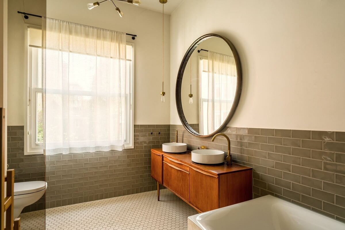 A Colorful Family Home with Open-Plan Spaces in Amsterdam 16 half tiled bathroom with large round mirror and wooden vanity