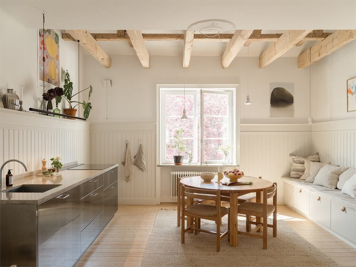 Wooden Details in a Light Duplex Apartment in Sweden 4 kitchen with stainless steel cabinets round table and wooden beams nordroom