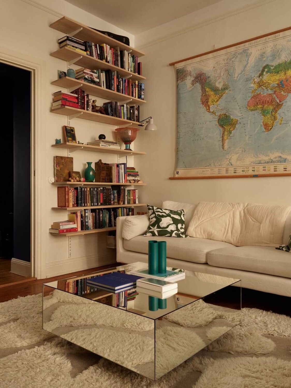 Warm Tones and a Blue Hallway in a Stockholm Apartment 4 living room with mirror coffee table and bookshelves
