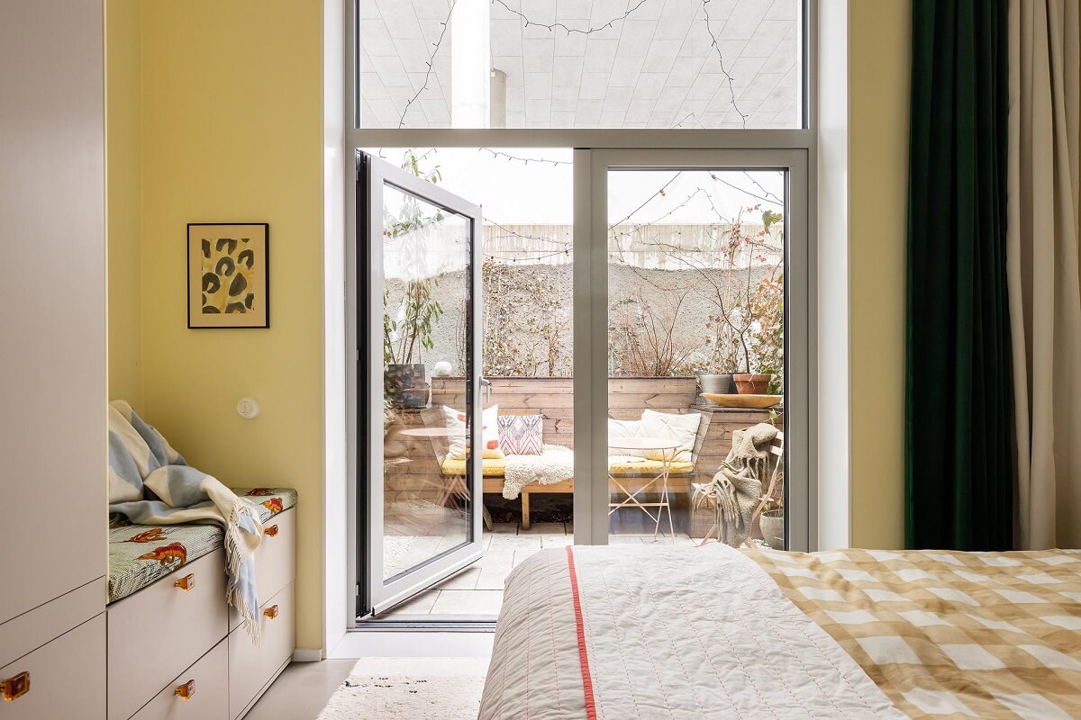 A Unique Basement Apartment in Stockholm 9 pale yellow bedroom with built in wardrobes with bench and balcony nordroom