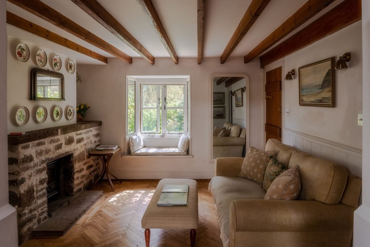 Ochre Yellow and Green Tones in a Cozy Welsh Cottage 10 sitting room with stone fireplace and wooden beams