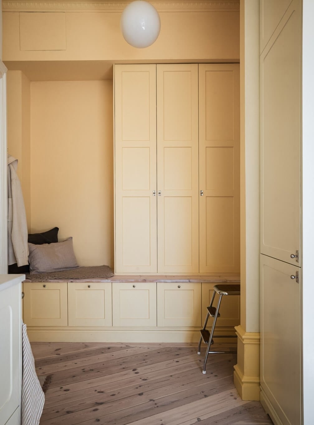 Warm Color Tones in a Scandinavian Apartment 12 yellow hallway with built in cabinets and bench
