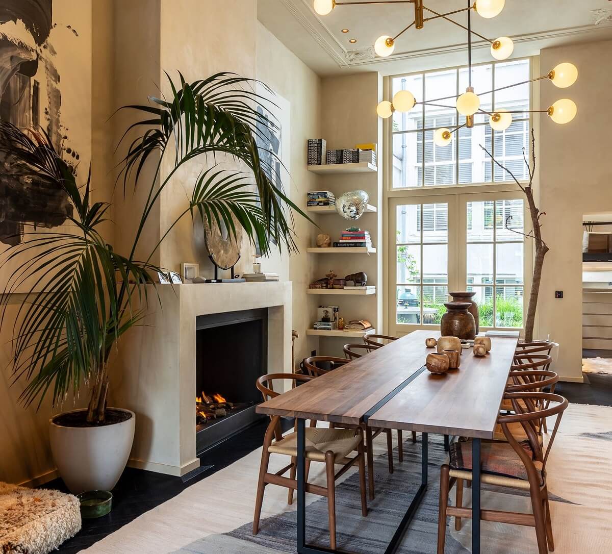 A Luxurious Apartment in an Amsterdam Canal House 1 dining room with floor to ceiling window fireplace and large wooden table with wishbone chairs