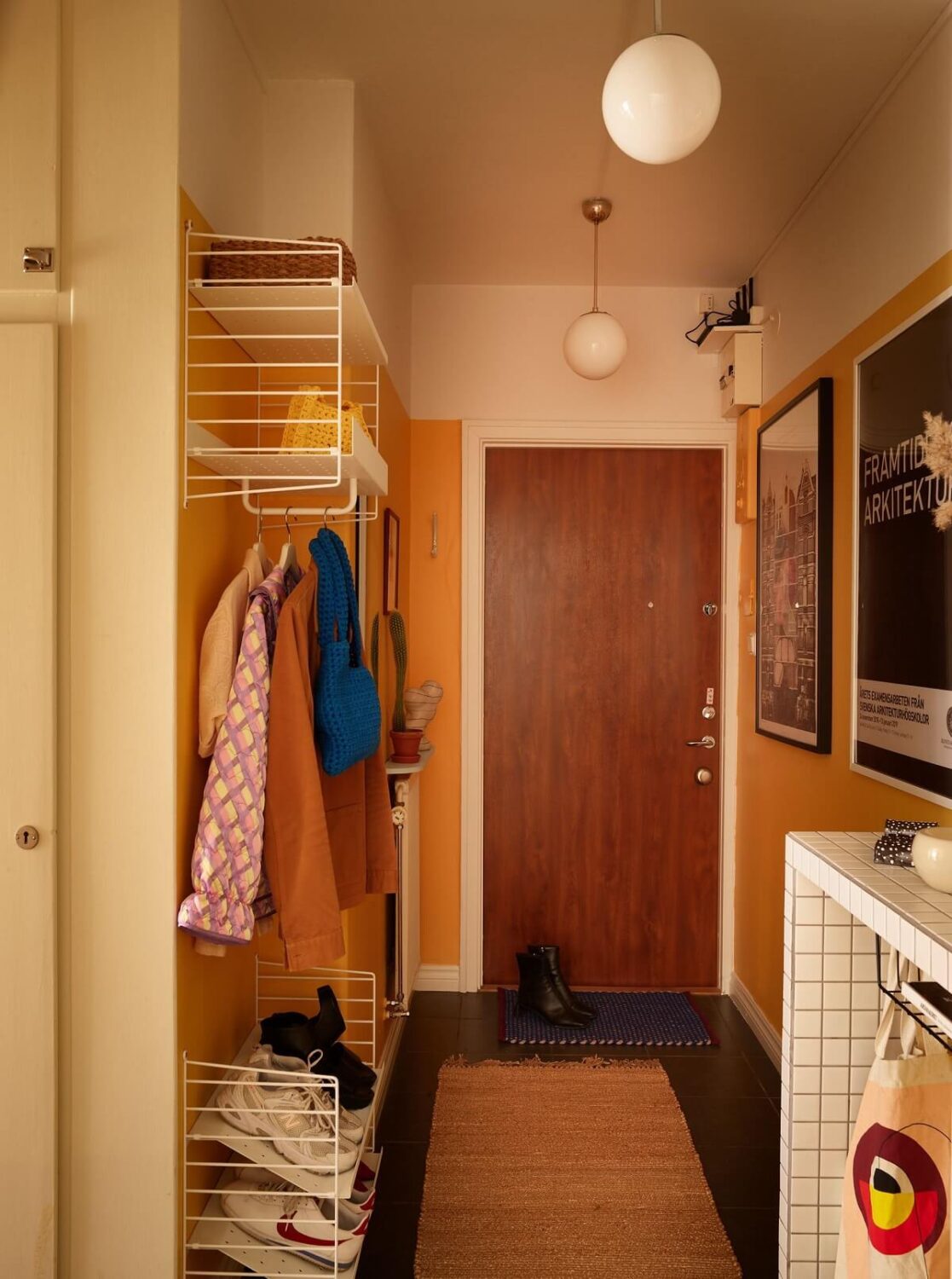A Small Light Filled Apartment with Plants and Color 21 hallway with orange walls and open cabinet nordroom